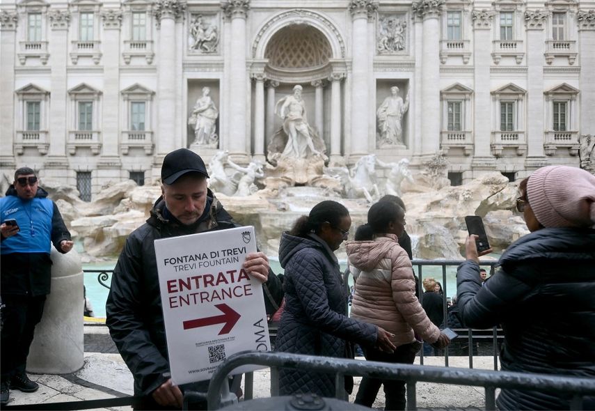 Un hombre sostiene un cartel con la inscripción Entrada frente a la Fontana de Trevi, en el centro de Roma, el 19 de diciembre de 2025.