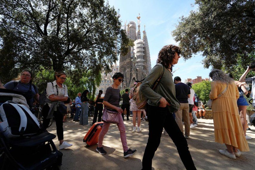 Una mujer tira de una maleta mientras pasa por la basílica de la Sagrada Familia en Barcelona el 13 de abril de 2024.