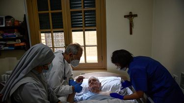 Félix Murillo, residente de la casa de ancianos El Buen Pastor (al centro), es asistido por el doctor Juan José Unzue y la enfermera Karen Oses mientras recibe la vacuna de Pfizer contra el coronavirus en Pamplona, España, el jueves 14 de enero de 2021. 