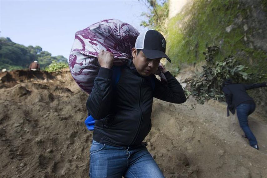 Un hombre carga sus pertenencias, tras un deslizamiento de tierra que dejo numerosos desaparecidos y damnificados en la colonia El Cambray II del municipio de Santa Catarina Pinula, a unos 22 kilómetros de Ciudad de Guatemala (Guatemala). (EFE)