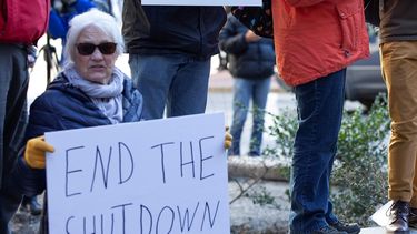 Una mujer sostiene un cartel que pide el fin del cierre parcial del Gobierno durante una protesta frente a una oficina de correos en Boston, Massachusetts.