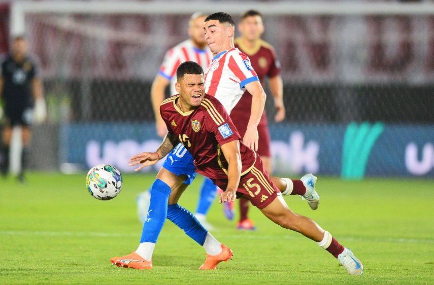 El defensor venezolano Miguel Navarro pelea por despejar el balón frente al atacante paraguayo Miguel Almirón, el 15 de octubre de 2024.