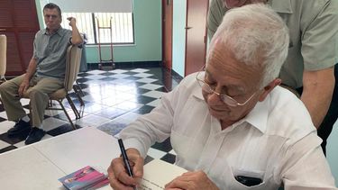 El autor Julio Estorino firma un ejemplar de su libro.