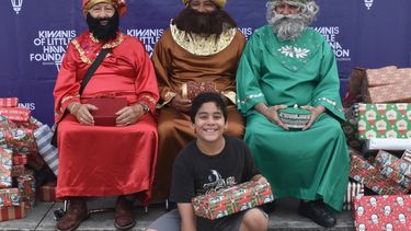 Un niño posa junto a los Reyes Magos después de recibir un juguete. 