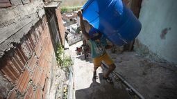Un niño sube unas escaleras cargado con dos recipientes vacíos que llenará con el agua suministrada por un camión cisterna del gobierno, en el vecindario de Petare, en Caracas, Venezuela, el 15 de junio de 2020. El colapso económico de Venezuela ha dejado a la mayoría de los hogares sin un suministro de agua corriente confiable.&nbsp;