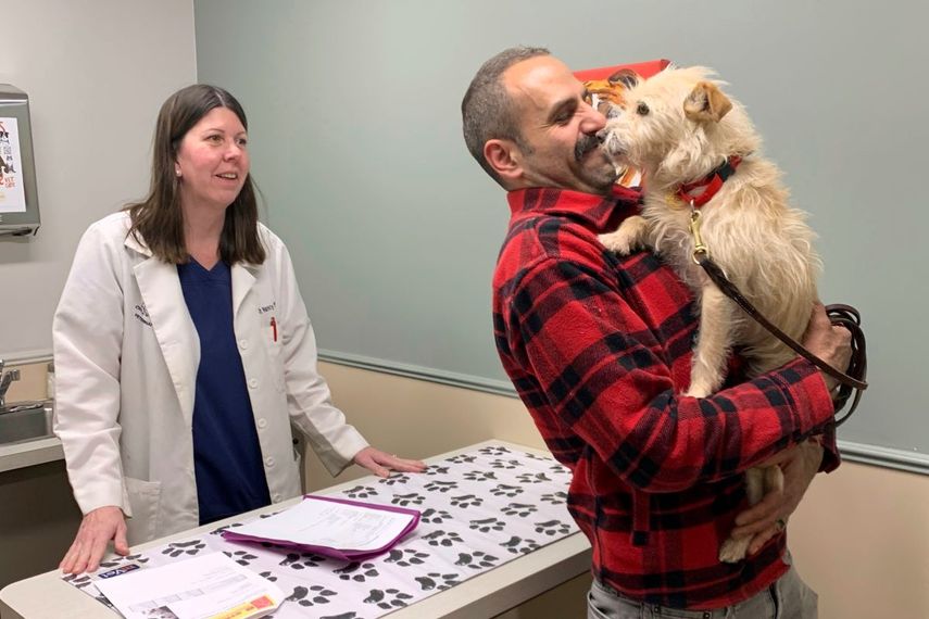 En esta imagen cortesía de Corinne Martin, Mehrad Houman sostiene a su perra, Mishka, después de ser examinada por la veterinaria Nancy Pillsbury, el viernes 29 de marzo de 2024, en Harper Woods, Michigan.&nbsp;