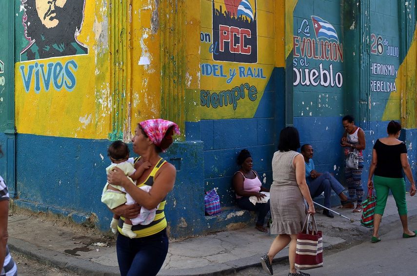 Varias personas caminan frente a una pared con grafitis de Hugo Chávez y Ernesto Ché Guevara hoy, jueves 21 de diciembre de 2017, en una calle de La Habana (Cuba). EFE/Alejandro Ernesto