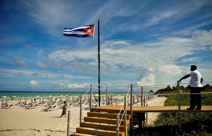 Un turista camina cerca de una bandera nacional cubana en el Hotel Melia International Varadero en la provincia de Matanzas, el 23 de octubre de 2020. Varadero, el balneario más importante de Cuba, reabre al turismo internacional, en medio de la pandemia del coronavirus.