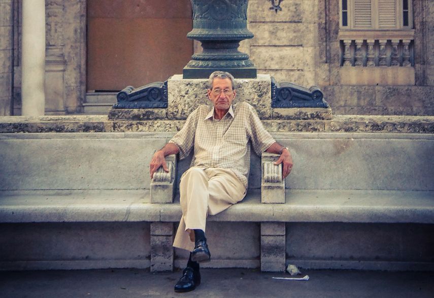 Un hombre aguarda, sentado en un banco, en una calle de la capital cubana.