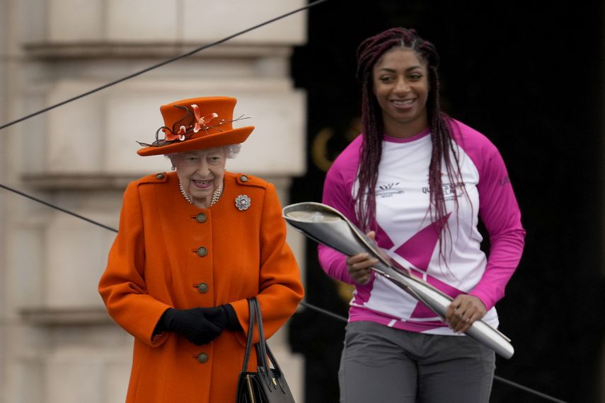 La atleta británica Kadeena Cox, quien ganó dos medallas de oro en los Juegos Paralímpicos de Río 2016, recibe el testigo de la reina Isabel II de Inglaterra para dar inicio a la carrera de relevo previa a los Juegos de la Commonwealth 2022, afuera del Palacio de Buckingham en Londres, el jueves 7 de octubre de 2021.