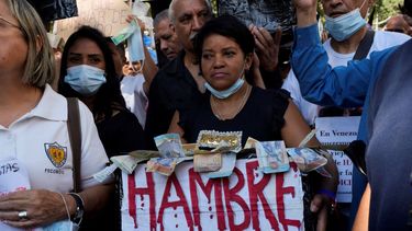 Un manifestante lleva una caja de billetes de bolívar que dice hambre durante una manifestación por mejores salarios y beneficios en Caracas, Venezuela, el miércoles 11 de enero de 2023.