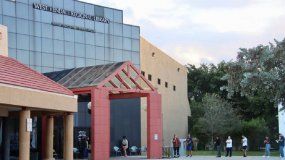 Una persona entra a votar y otra sale tras depositar su voto, en la biblioteca de West Kendall Regional Library.