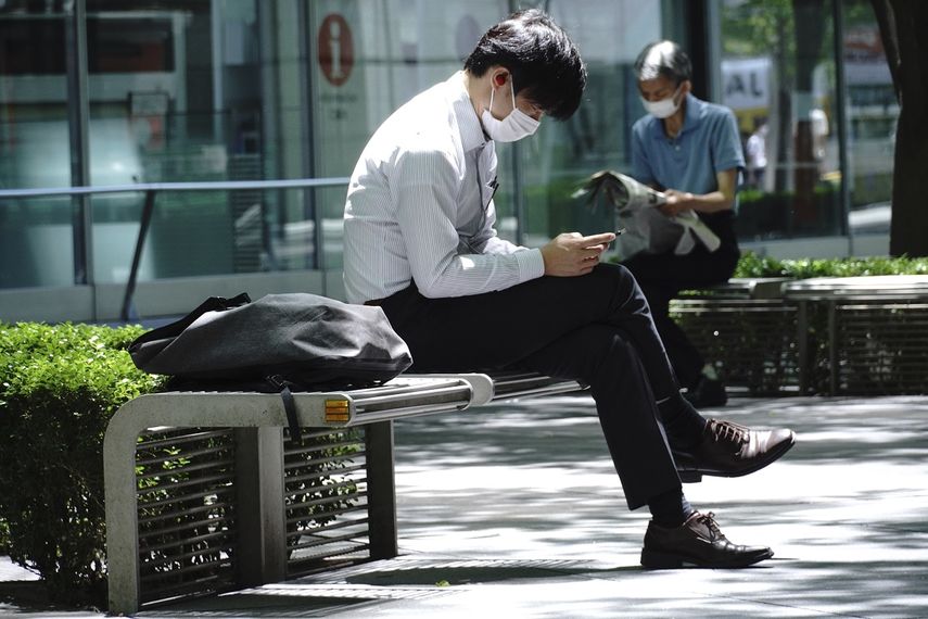 Un hombre, con mascarilla para tratar de frenar la curva de contagios del coronavirus, descansa en un banco en Tokio, el 14 de mayo de 2020. 