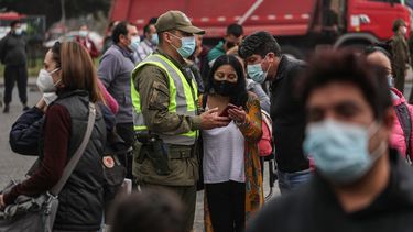 Un oficial de policía verifica los permisos de tránsito de las personas el jueves 1 de abril de 2021 en medio de una cuarentena por la pandemia de coronavirus afuera del Mercado Central, donde los compradores aguardan a comprar pescado para la Semana Santa, en Santiago, Chile.