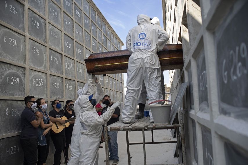 En esta imagen, tomada el 30 de abril de 2020, la familia observa mientras los enterradores introducen el f&eacute;retro con los restos mortales de Carmen Valeria, de 76 a&ntilde;os y que se cree que muri&oacute; por coronavirus, en un nicho, en R&iacute;o de Janeiro, Brasil.&nbsp;