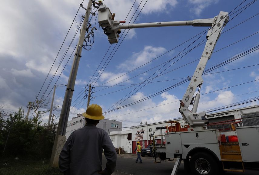 Empleados de la Autoridad de Energía Eléctrica (AEE) trabajan en un poste caído por el paso del huracán María.