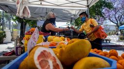 Un vendedor atiende a un cliente en un puesto de frutas.