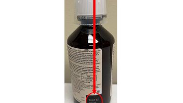 La foto distribuida por la Administración de Alimentos y Medicamentos (FDA) muestra la ubicación del número de lote del jarabe para la tos Robitussin retirado de la venta