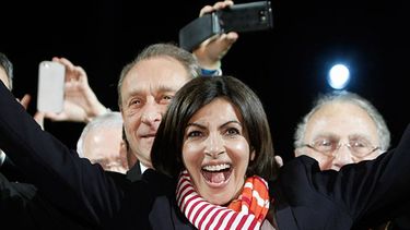 La socialista Anne Hidalgo (centro), sonríe, con el alcalde saliente Bertrand Delanoe a su espalda, durante un discurso después de anunciarse los resultados de la segunda vuelta de las elecciones municipales, en París.(Foto AP/Thibault Camus)