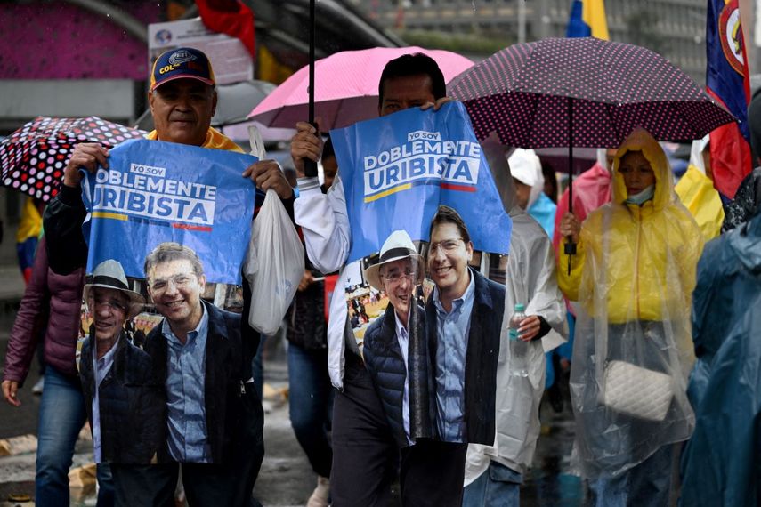 Manifestantes exhiben carteles que representan al presidente colombiano Álvaro Uribe (izq.) y al candidato presidencial de derecha Miguel Uribe —sin parentesco con Uribe y quien sufrió un intento de asesinato en junio— durante una protesta en apoyo al expresidente, quien se encuentra en arresto domiciliario, en Bogotá el 7 de agosto de 2025. 