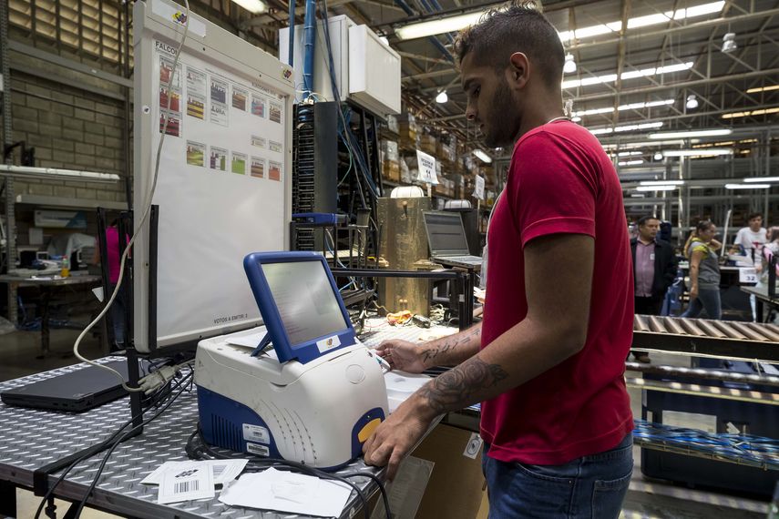 Un trabajador del Consejo Nacional Electoral de Venezuela (CNE) revisa una de las máquinas que se utilizan en las elecciones presidenciales.