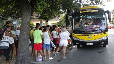 VArios pasajeros esperan para subir a un taxi-bus, medio de transporte en manos de particulares agrupados en cooperativas en Cuba.