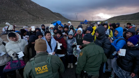 Inmigrantes irregulares en la frontera de Estados Unidos mostrando pasaportes a agentes de la Patrulla Fronteriza.