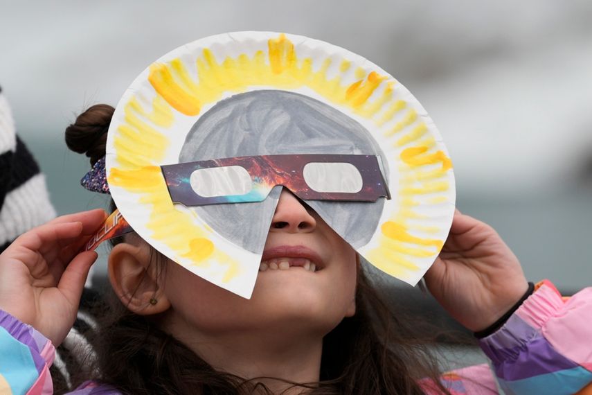 Una persona usa gafas especiales para observar el eclipse solar total. Observe el eclipse solar total desde las Cataratas del Niágara, Ontario, el lunes 8 de abril de 2024.