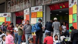 Un grupo de personas hace fila para comprar salchichas y queso en una tienda cerca del mercado municipal de Quinta Crespo que muestra los precios en dólares en Caracas, Venezuela.