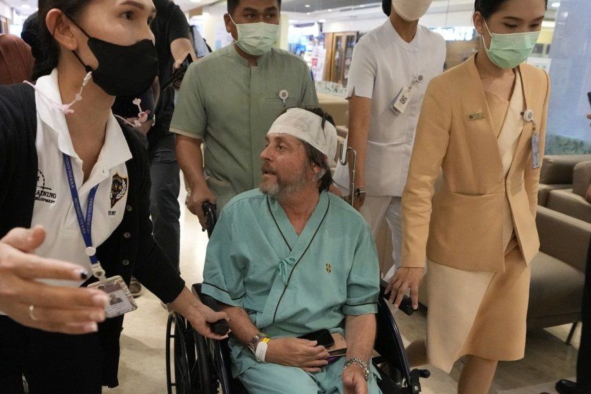 Un pasajero australiano, en el centro, que resultó herido en un vuelo afectado por turbulencias, habla con periodistas en el hospital Samitivej Srinakarin en Bangkok, Tailandia, el jueves 23 de mayo de 2024. El vuelo SQ321 iba desde el aeropuerto londinense de Heathrow a Singapur cuando encontró fuertes turbulencias el martes.&nbsp;