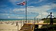 Un turista camina cerca de una bandera nacional cubana en el Hotel Melia International Varadero en la provincia de Matanzas, el 23 de octubre de 2020. Varadero, el balneario más importante de Cuba, reabre al turismo internacional, en medio de la pandemia del coronavirus.
