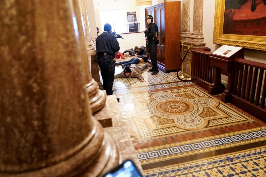 Agentes de la policía del Capitolio retienen a punta de pistola a unos manifestantes cerca del recinto de la Cámara de Representantes, en el Capitolio, en Washington, el miércoles 6 de enero de 2021.