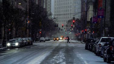 Un peatón utiliza un paraguas mientras cruza la Avenida Liberty en el centro de Pittsburgh, mientras comienza a nevar en medio de una tormenta, el domingo 16 de enero de 2022.