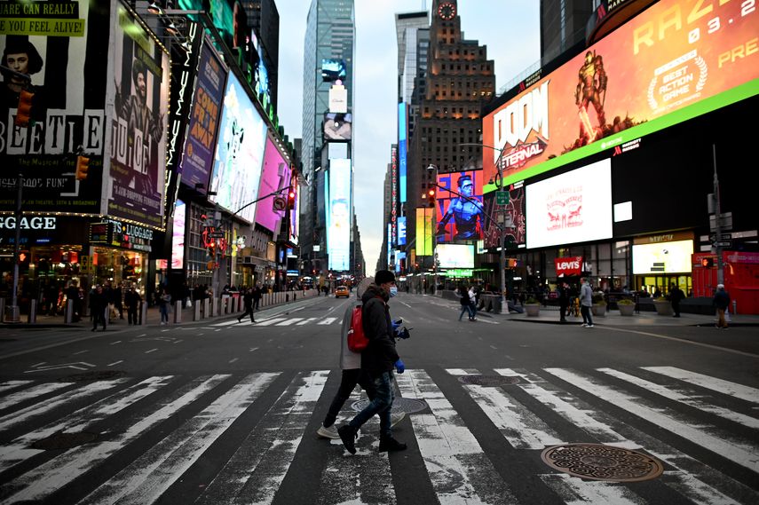 Personas con m&aacute;scaras cruzan la calle en Times Square, en Manhattan, el 17 de marzo de 2020 en la ciudad de Nueva York.&nbsp;