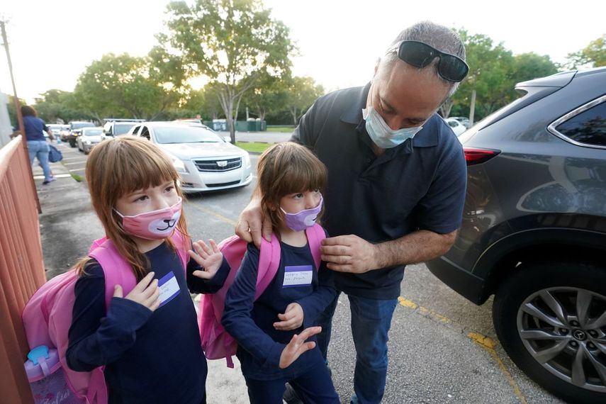 Anthony Sacco deja a sus hijas Angelina, de 7 años, (izquierda), y Victoria, de 5, para su primer día de clases en la primaria Fox Trail, el viernes 9 de octubre de 2020, en Davie, Florida.&nbsp;