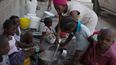 Una mujer acompañada de niños cocina en el refugio para familias desplazadas por la violencia de las pandillas en Puerto Príncipe, Haití, el jueves 9 de diciembre de 2021 (AP Foto