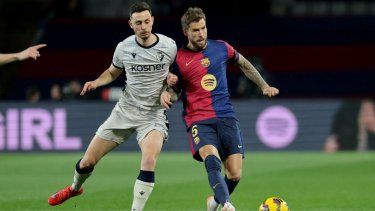 El atacante del Osasuna, Raúl García (izquierda), y el defensor del Barcelona, Iñigo Martínez, pelean por el balón en un partido, el 27 de marzo de 2025.