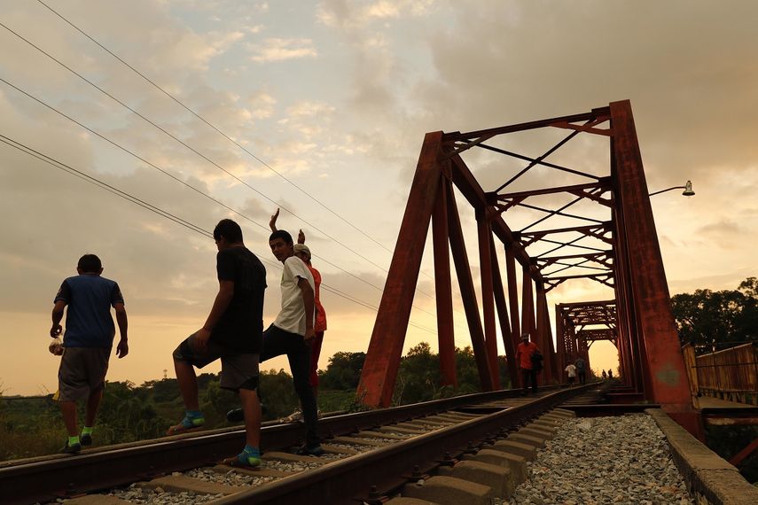 Migrantes hondureños conversan en una vía férrea de la población de Huixtla (México) donde permanecen en su travesía hacia Estados Unidos.&nbsp;