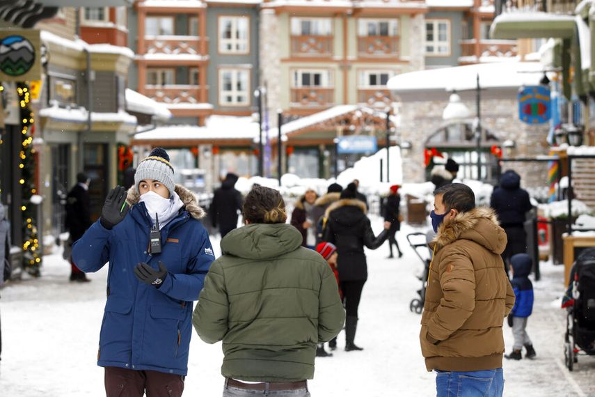 La empleada Dustin Martinez, del Centro de Esquí Blue Mountain Resort, informa a huéspedes del cierre del lugar en Ontario, Canadá, el sábado 26 de diciembre, en el primer día de una paralización de actividades y confinamientos en la provincia debido a un incremento de los casos diarios de COVID-19.