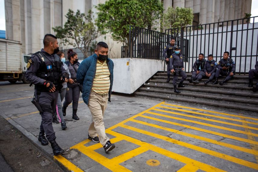 David Coronado Pérez, quien supuestamente es parte de una red de trata de personas, es escoltado por un oficial al final de su audiencia en la corte, en Ciudad de Guatemala, el viernes 4 de febrero de 2022.
