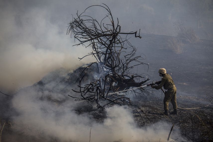 Un soldado israelí combate un incendio causado por un dispositivo incendiario lanzado desde la Franja de Gaza, cerca de la valla que separa Israel de Gaza, el lunes 24 de junio de 2019.&nbsp;
