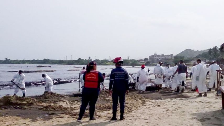 Trabajadores recogen de manera rudimentaria el petróleo vertido en el mar tras serio accidente en la Refinería del Palito, en Venezuela