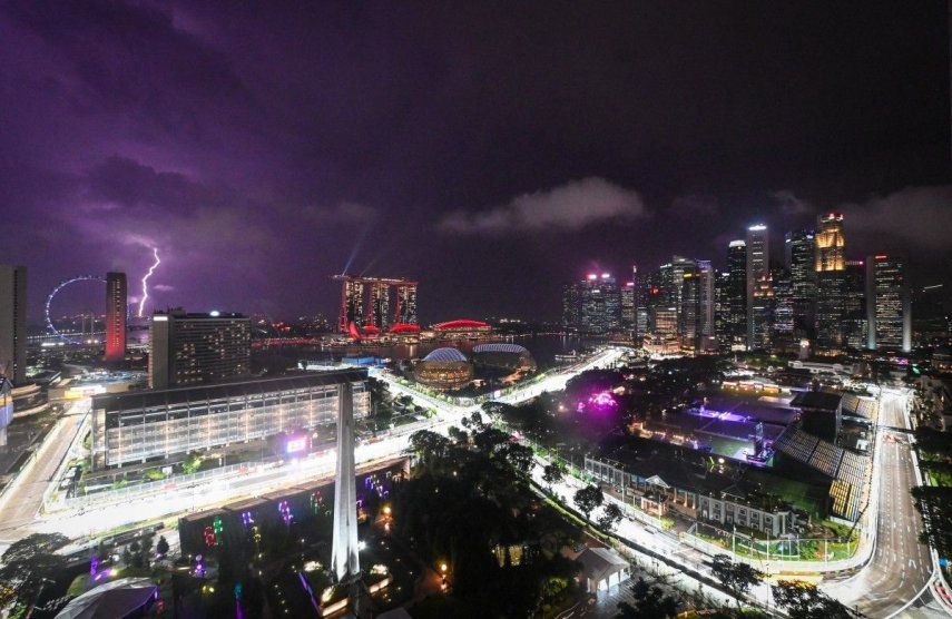Esta foto muestra el circuito iluminado para el próximo Gran Premio de Fórmula 1 de Singapur en el Circuito Urbano de Marina Bay, mientras un rayo (izq.) ilumina el cielo de Singapur el 1 de octubre de 2025.