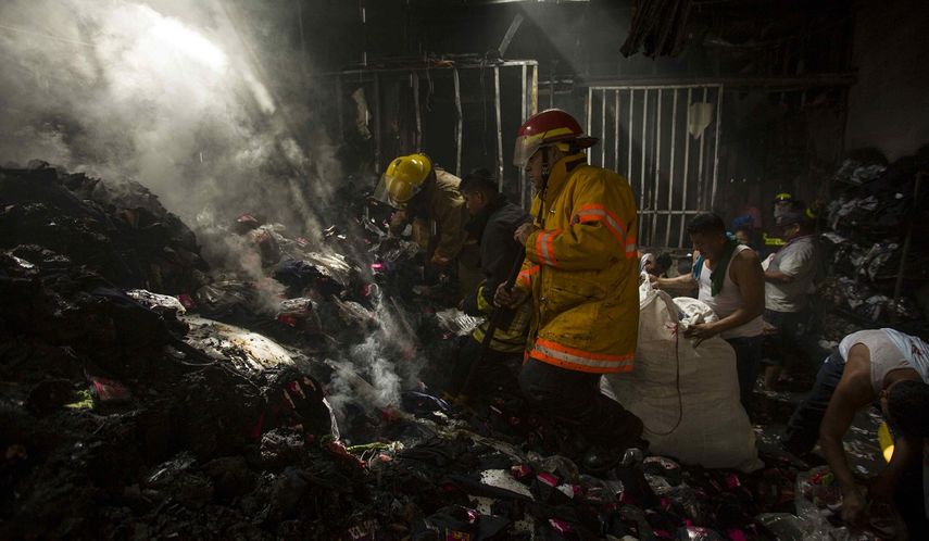 Bomberos apagan las llamas de un incendio que destruyó un establecimiento comercial este 27 de diciembre de 2017, en Managua, Nicaragua.