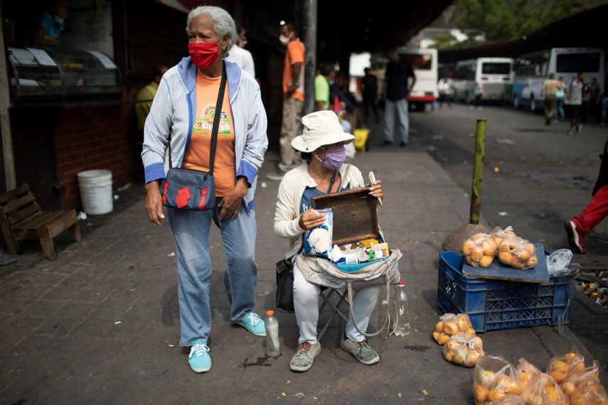   Vendedores callejeros usan mascarillas para protegerse del nuevo coronavirus mientras esperan clientes en Caracas, Venezuela, el martes 21 de abril de 2020.   