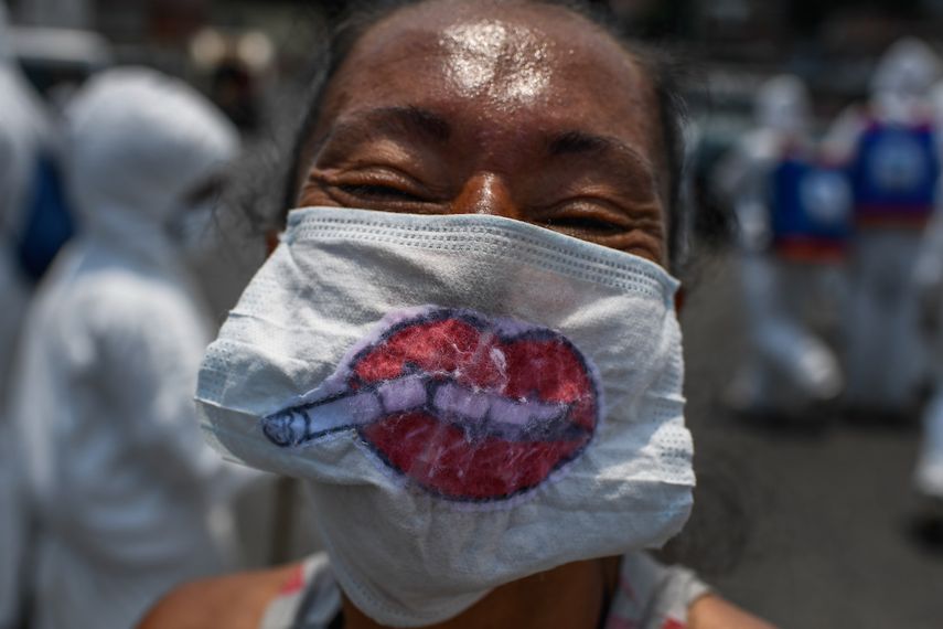 Una mujer en una barriada de Petare muestra una mascarilla de protección contra el coronavirus con un dibujo.     