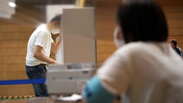 Una trabajadora de la administración electoral local mira mientras un votante prepara su boleta en las elecciones parlamentarias en un centro de electoral el domingo 10 de julio de 2022 en Tokio.&nbsp;