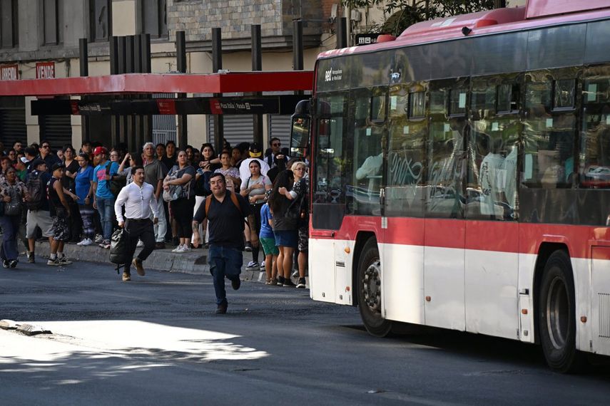La gente espera mientras asiste en una parada de autobús durante un apagón en Santiago el 25 de febrero de 2025.