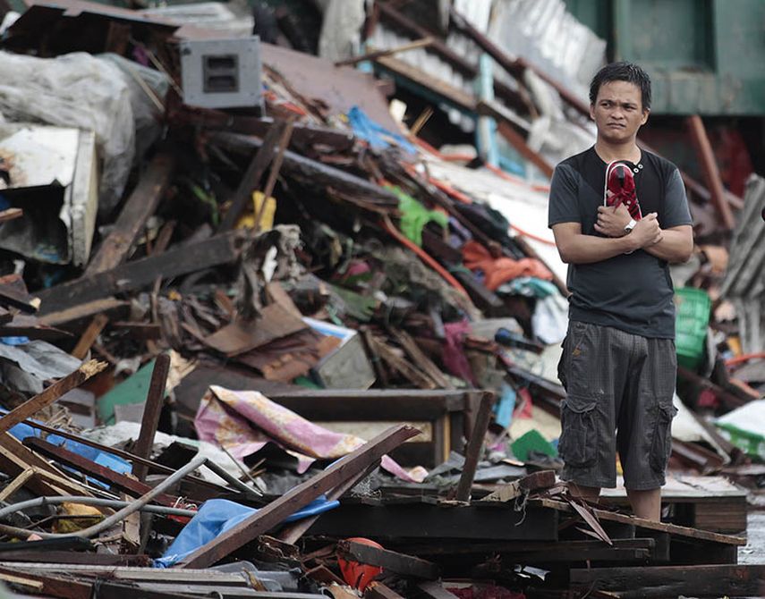 Un superviviente del tifón Haiyan permanece de pie en silencio entre las casas dañadas en la ciudad de Tacloban, Filipinas, el lunes 11 de noviembre de 2013. (Foto AP/Aaron Favila)