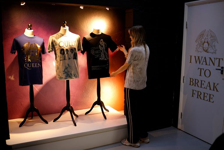 Un dependiente posa con mercancía oficial del legendario grupo de rock británico Queen a la venta en su tienda recién inaugurada en el centro de Londres el 27 de septiembre de 2021.